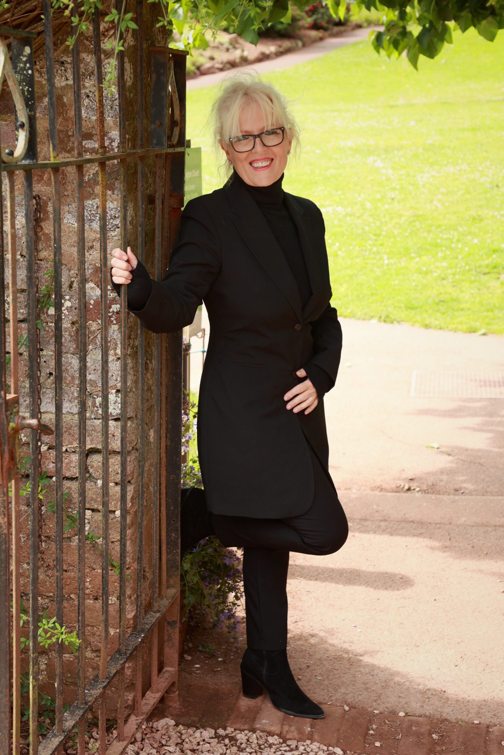 a picture of Paula C Whitfield standing next to a railing and wearing a black suit and Paula is the founder of lose weight be happy and ambiance hypnotherapy.